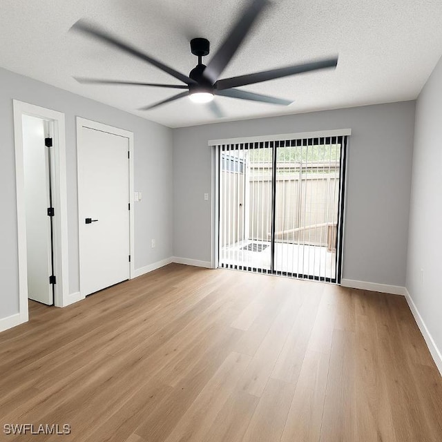 empty room featuring a ceiling fan, baseboards, light wood-type flooring, and a textured ceiling