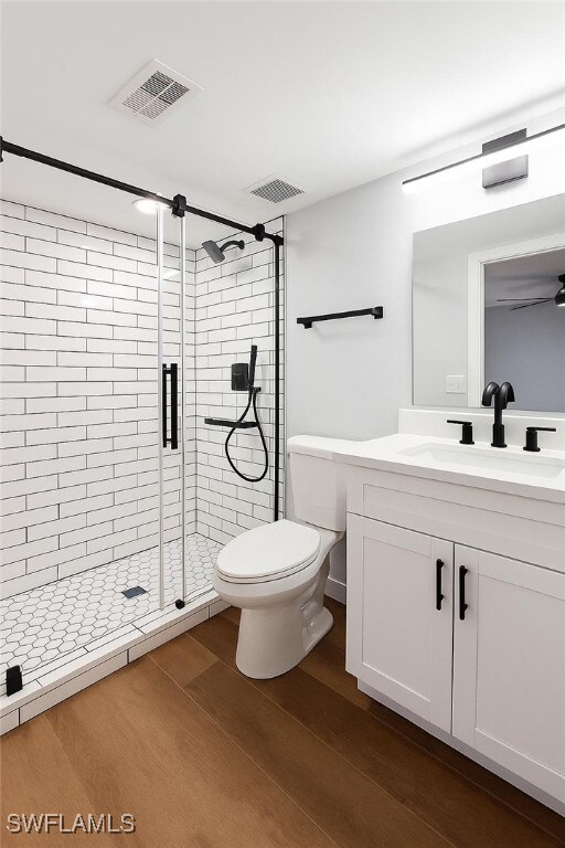 bathroom with vanity, wood finished floors, a shower stall, and toilet