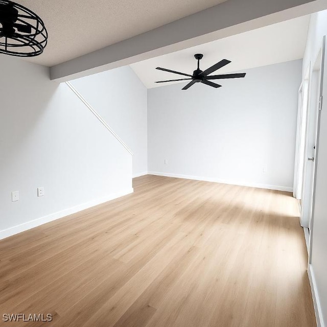 unfurnished living room with light wood-style flooring, ceiling fan, baseboards, and vaulted ceiling