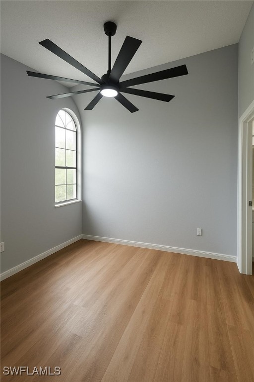 spare room featuring a ceiling fan, light wood-style floors, and baseboards