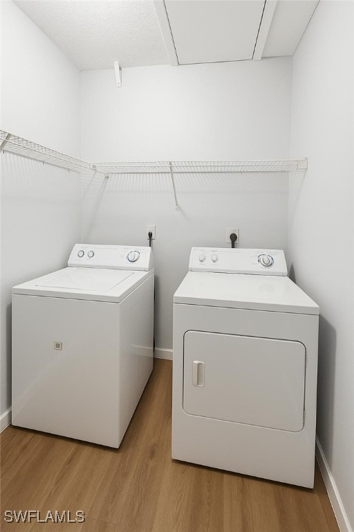 laundry area featuring washing machine and clothes dryer, light wood-style flooring, and baseboards