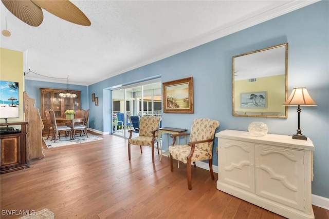 1155 Sandpiper St Unit G2, Naples, FL 34102 - sitting room with baseboards, light wood-style flooring, crown molding, a chandelier, and a ceiling fan