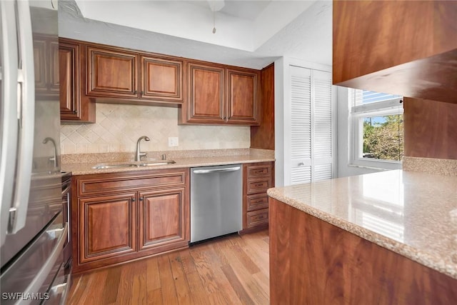 1155 Sandpiper St Unit G2, Naples, FL 34102 - kitchen with a sink, appliances with stainless steel finishes, light wood-style flooring, light stone counters, and decorative backsplash