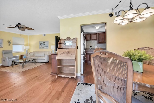 1155 Sandpiper St Unit G2, Naples, FL 34102 - dining room featuring light wood finished floors, ceiling fan, crown molding, and a chandelier