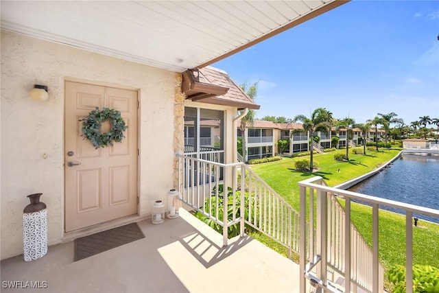 1155 Sandpiper St Unit G2, Naples, FL 34102 - entrance to property featuring a water view, stucco siding, a lawn, and a balcony