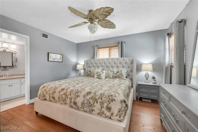 1155 Sandpiper St Unit G2, Naples, FL 34102 - bedroom featuring wood-type flooring, a sink, a textured ceiling, ceiling fan, and connected bathroom