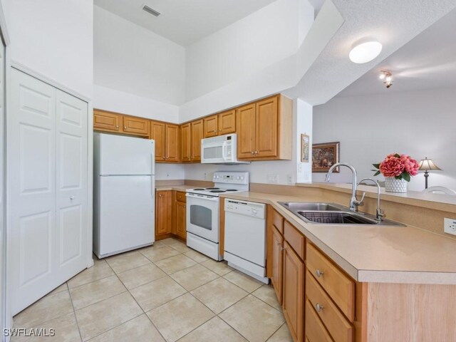 26660 Rosewood Pointe Cir Unit 205, Bonita Springs, FL 34135 - kitchen with white appliances, a sink, a peninsula, light tile patterned floors, and light countertops