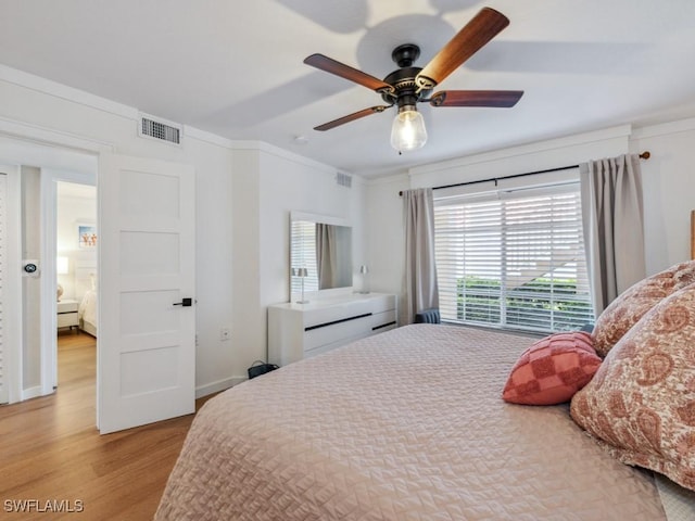 bedroom with wood finished floors, ornamental molding, and a ceiling fan