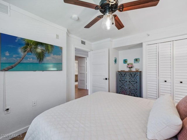 bedroom featuring baseboards, a closet, ceiling fan, ornamental molding, and wood finished floors