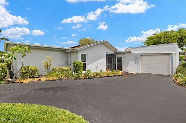 3275 Boca Ciega Dr Unit D49, Naples, FL 34112 - ranch-style house with stucco siding, a garage, asphalt driveway, and solar panels