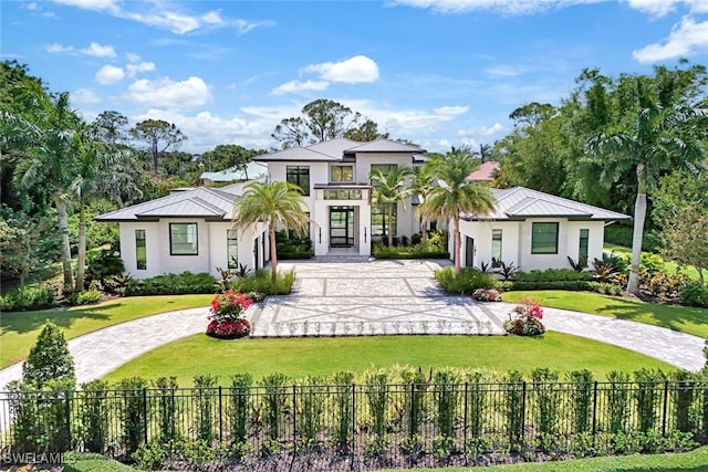 493 Carica Rd, Naples, FL 34108 - view of front facade featuring curved driveway, stucco siding, and a standing seam roof