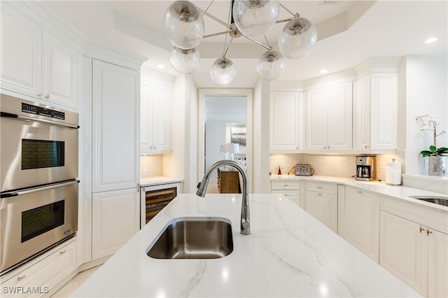 940 Cape Marco Dr Unit 1703, Marco Island, FL 34145 - kitchen with stainless steel double oven, a sink, beverage cooler, white cabinets, and recessed lighting