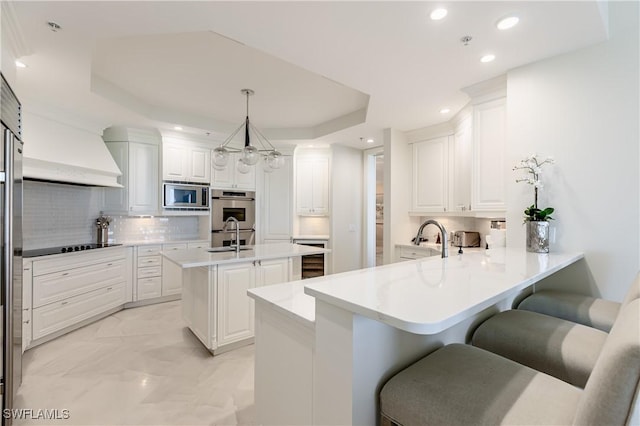 940 Cape Marco Dr Unit 1703, Marco Island, FL 34145 - kitchen featuring stainless steel appliances, a peninsula, a sink, a raised ceiling, and backsplash