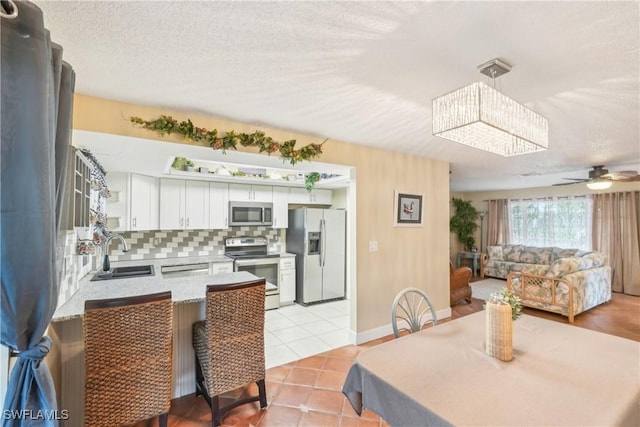dining room featuring light tile patterned floors, ceiling fan, a textured ceiling, and baseboards