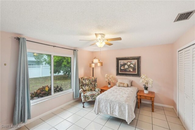 bedroom featuring a closet, ceiling fan, baseboards, light tile patterned flooring, and a textured ceiling