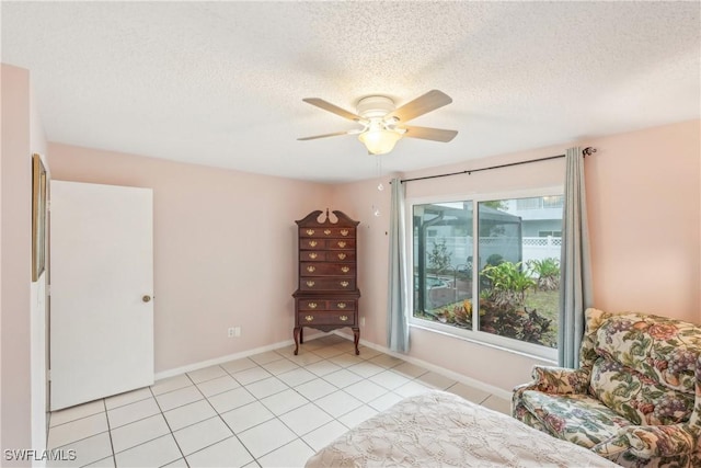 bedroom featuring a textured ceiling, light tile patterned flooring, a ceiling fan, and baseboards