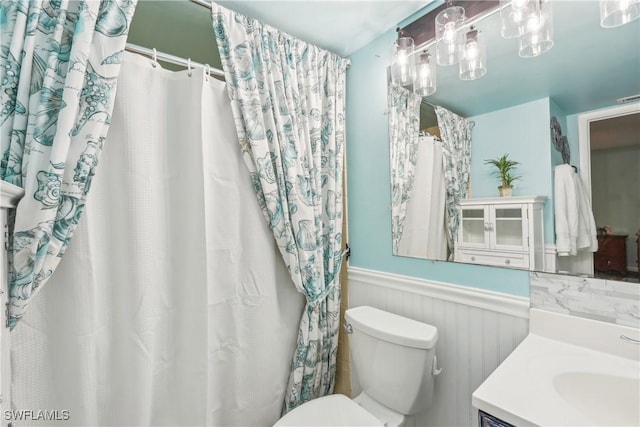 full bathroom featuring wainscoting, toilet, and vanity