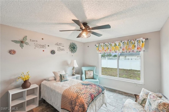 bedroom with a textured ceiling, ceiling fan, and baseboards