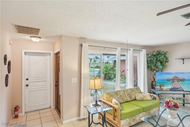 living room with a textured ceiling, baseboards, and light tile patterned floors