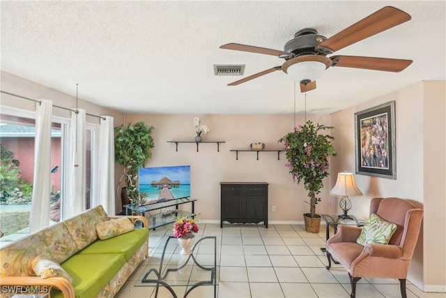 living room with healthy amount of natural light, baseboards, ceiling fan, tile patterned flooring, and a textured ceiling