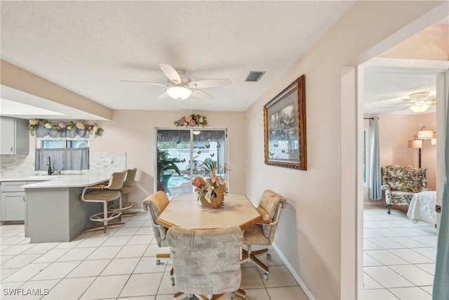 dining space with ceiling fan, plenty of natural light, light tile patterned floors, and a textured ceiling