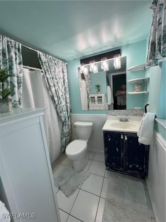 full bath featuring vanity, tile patterned flooring, toilet, and wainscoting