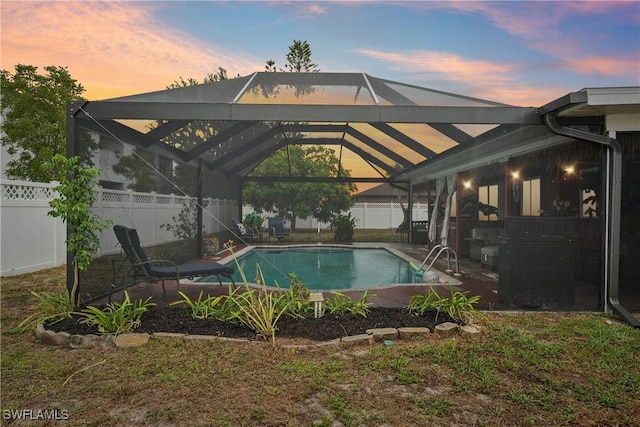 pool at dusk featuring a fenced backyard, a lanai, and a patio