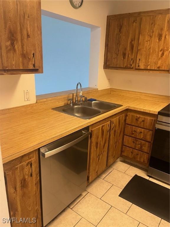 kitchen featuring stainless steel dishwasher, a sink, light countertops, light tile patterned floors, and stove