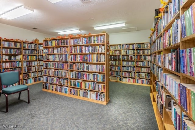 sitting room with bookshelves, carpet flooring, and a textured ceiling
