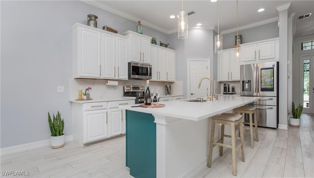 7874 Bucks Run Dr, Naples, FL 34120 - kitchen with stainless steel appliances, a sink, white cabinets, a kitchen breakfast bar, and ornamental molding