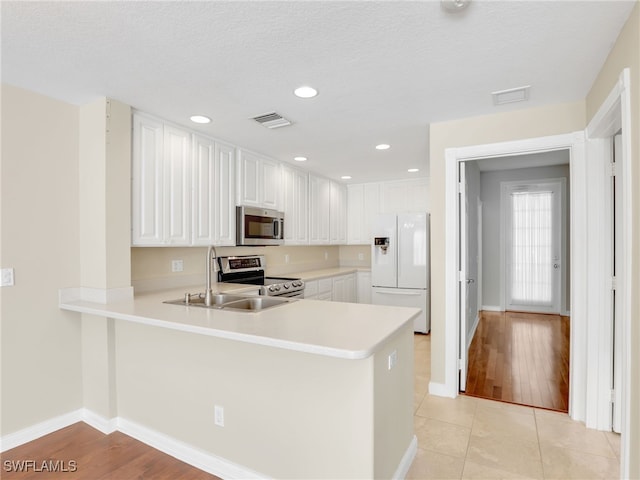 15329 Laughing Gull Ln, Bonita Springs, FL 34135 - kitchen with appliances with stainless steel finishes, a peninsula, light countertops, white cabinetry, and light tile patterned floors