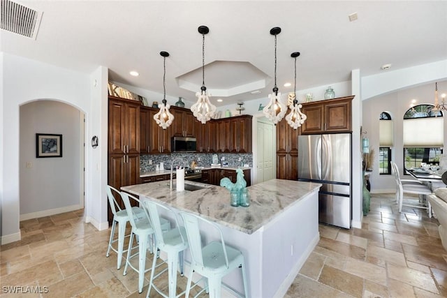 208 SW 15th St, Cape Coral, FL 33991 - kitchen with stainless steel appliances, a chandelier, stone tile floors, tasteful backsplash, and a raised ceiling