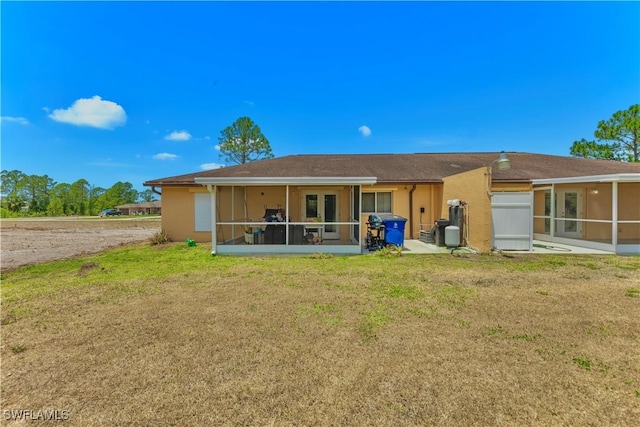 869/871 Eisenhower Blvd, Lehigh Acres, FL 33974 - rear view of property featuring a sunroom, a yard, and stucco siding