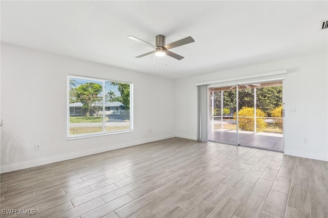 empty room with ceiling fan, plenty of natural light, and wood finished floors