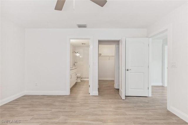 unfurnished bedroom with baseboards, ensuite bathroom, light wood-style floors, a spacious closet, and a closet