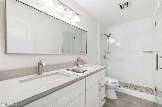 full bath with a shower stall, double vanity, and toilet
