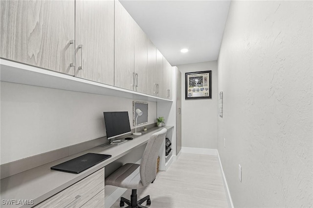 office featuring built in desk, baseboards, light wood-style flooring, and recessed lighting