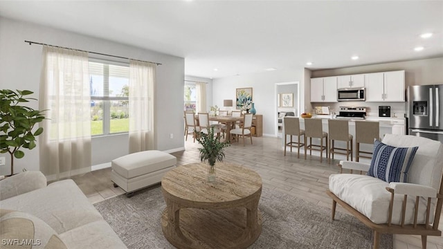living area with light wood finished floors, recessed lighting, and baseboards