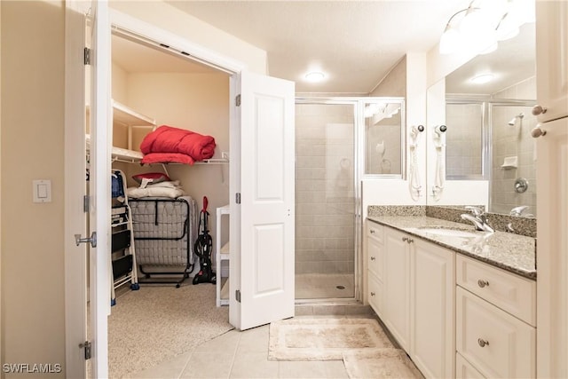 2825 Palm Beach Blvd Unit 203, Fort Myers, FL 33916 - bathroom featuring a stall shower, tile patterned flooring, vanity, and a walk in closet