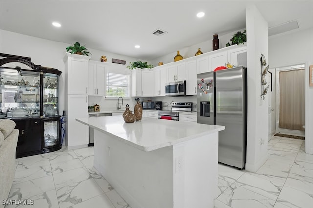 4174 58th Ave NE, Naples, FL 34120 - kitchen with appliances with stainless steel finishes, light marble finish floors, recessed lighting, white cabinetry, and a center island