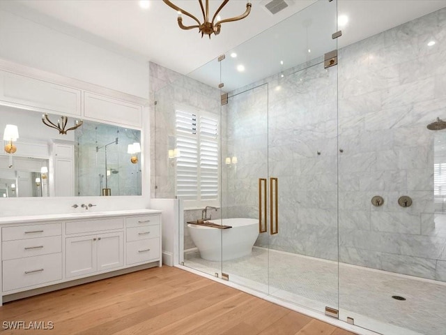 186 N St, Naples, FL 34108 - full bath with a stall shower, a freestanding tub, vanity, wood finished floors, and a chandelier