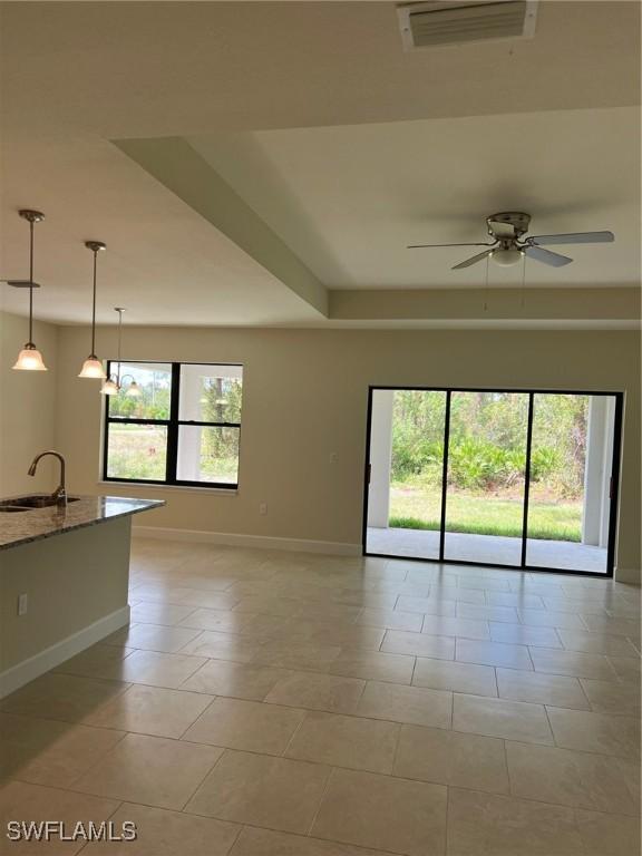 spare room with a sink, baseboards, ceiling fan, and light tile patterned floors