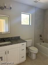 bathroom featuring toilet, vanity, and washtub / shower combination