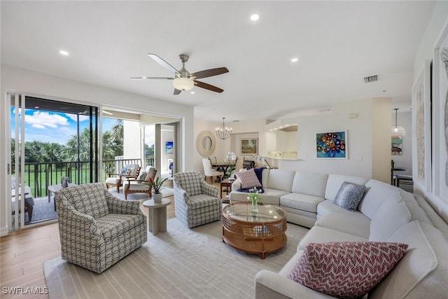 living area with light wood-style flooring, ceiling fan, recessed lighting, and a chandelier