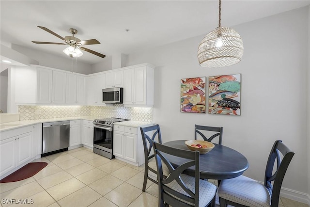 kitchen with stainless steel appliances, backsplash, a ceiling fan, a sink, and light countertops