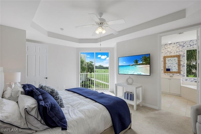 bedroom with a raised ceiling, access to exterior, multiple windows, and ensuite bathroom