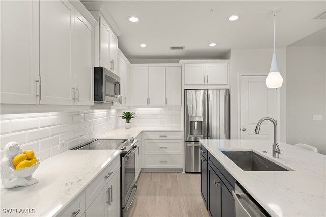 2647 Seychelles Cir Unit 2203, Naples, FL 34112 - kitchen featuring stainless steel appliances, a sink, white cabinetry, light stone counters, and pendant lighting