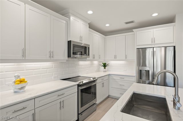 2647 Seychelles Cir Unit 2203, Naples, FL 34112 - kitchen featuring appliances with stainless steel finishes, a sink, white cabinetry, light stone counters, and recessed lighting