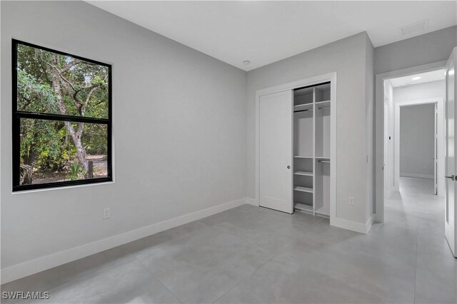 3366 72nd Ave NE, Naples, FL 34120 - unfurnished bedroom with baseboards, concrete floors, and a closet
