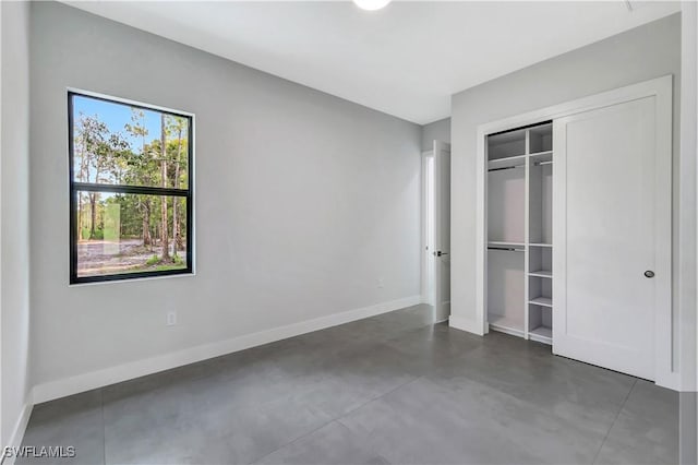 3366 72nd Ave NE, Naples, FL 34120 - unfurnished bedroom featuring baseboards, concrete floors, and a closet